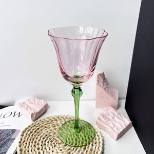 Detail of vintage pink flower wine glass with a green stem and elegant petal rim design