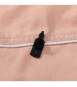 Macro shot of a black geometric enamel pin attached to pink twill fabric with white piping