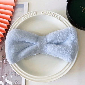 Close-up of light blue plush bow headband on a white decorative plate for skincare