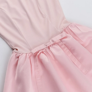 Detail shot of a pink sleeveless dress showing the satin bow and refined waist stitching