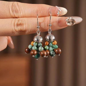 Detail of bohemian drop earrings with green glass beads and natural brown wood beads
