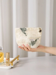 Off-white cotton linen makeup bag with green leaf embroidery and lace flower charms
