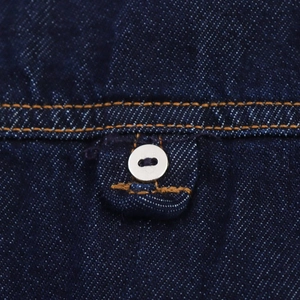 Gros plan sur le denim bleu foncé avec coutures orange et un bouton blanc rond