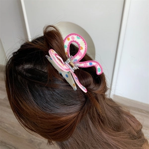 Detailed view of a polka dot butterfly hair claw clip securing a half-up ponytail