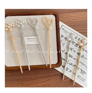 Detailed close-up of modern metallic hair pins with pearls on rustic wooden tray background