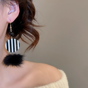 Close-up of retro black and white striped disc earrings with black plush fur balls