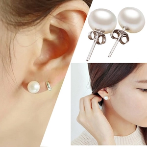 Close-up of S925 sterling silver studs with white freshwater pearls and model's ear shot