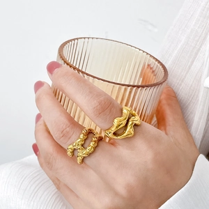 Golden titanium steel abstract fluid rings shown on model holding a glass cup