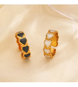 Macro view of gold-plated heart open rings with black and white inlay on silk background