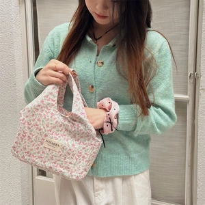 Close-up of floral lunch bag with SOZAKKA woven label held by a model in a natural setting
