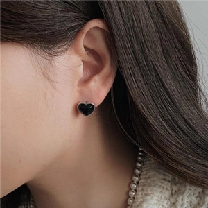 Minimalist black heart stud earrings in 925 sterling silver worn by a model