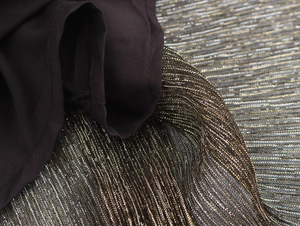 Macro shot of black fabric with golden glitter texture and elegant draped folds