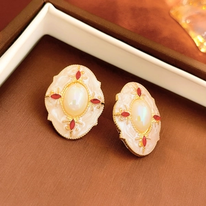 Close-up of vintage gold earrings with opal center and red stones in a jewelry box