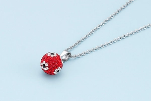 Detailed view of silver necklace with red rhinestone ball pendant featuring floral patterns