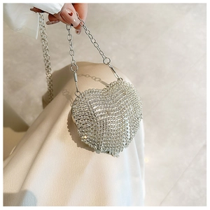 Close-up of a silver heart-shaped evening clutch bag with sparkling rhinestones and chain