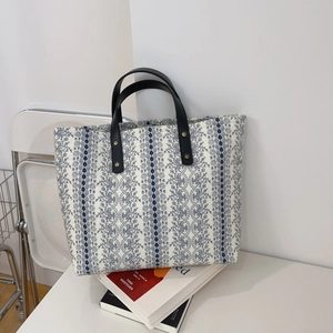 Detailed view of cream floral canvas tote bag with navy stripes and black leather handles