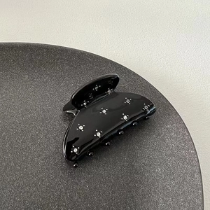 Elegant black shark hair claw clip with sparkling rhinestones on a minimalist tray