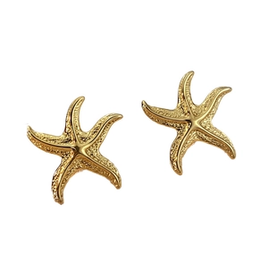 Orecchini a perno a forma di stella marina dorata con trama vintage su sfondo bianco