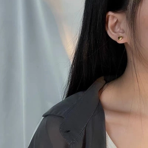 Elegant 18K gold-plated titanium heart stud earrings worn by a model in a close-up profile