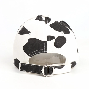 Detail view of cow print baseball cap featuring silver adjustable metal buckle on back