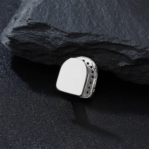 Macro shot of silver hip hop single tooth grillz on a dark textured stone background