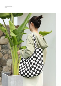Outdoor shot of a classic black and white checkered canvas tote bag worn on shoulder