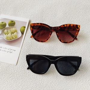 Close-up of stylish tortoiseshell and black cat-eye sunglasses on a textured surface