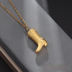 Detailed view of a gold-toned cowboy boot pendant necklace with intricate carvings