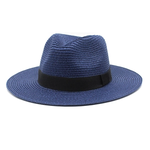 Detail of navy blue straw Panama hat featuring woven texture and black ribbon band