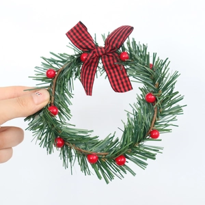 Detail of a mini Christmas wreath with green pine needles and a red-black plaid bow