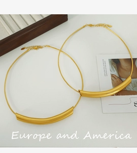 Detail shot of a minimalist 18k gold plated curved pipe pendant on a snake bone chain