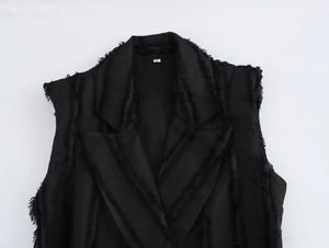 Gros plan d'une robe noire sans manches texturée avec détails de franges et revers