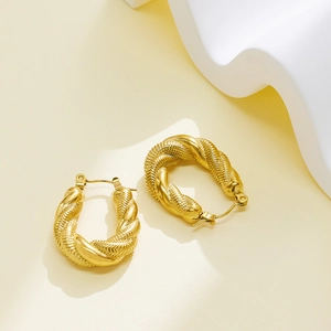 Golden twisted U-shaped hoop earrings with woven texture on a minimalist background