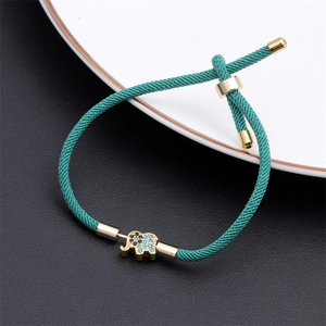 Detail of green woven bracelet with gold elephant charm featuring blue zircon inlays
