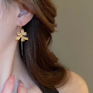 Detailed close-up of a gold iris flower drop earring on a model with elegant metallic texture