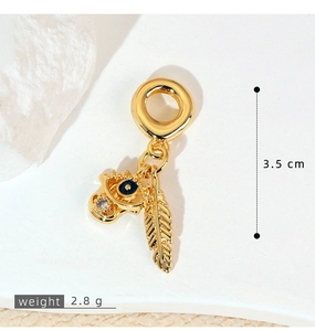 Detailed view of a gold Hamsa hand pendant with blue evil eye and crystal feather charm