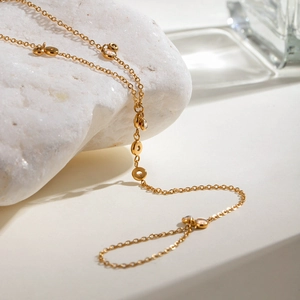 Detail of gold chain bracelet with white cubic zirconia charms on white stone base