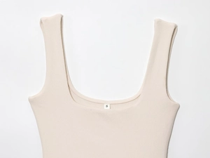 Detail of beige ribbed knit sleeveless top neckline with a visible size S label