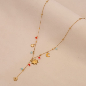 Chic gold Y-necklace with crystal sun, moon and star pendants on beige fabric