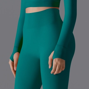 Detail of high waist seamless yoga leggings and long sleeve top with thumbholes in dark teal