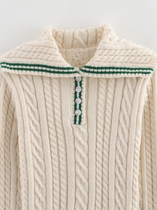 Detail of cream cable knit sweater showing green stripes and four-button collar