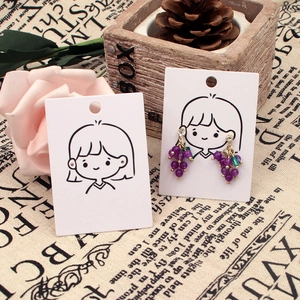Detail of purple grape-shaped earring with green leaf on rustic display setup