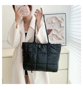 Close-up of black quilted puffer tote bag with classic large square pattern and soft straps