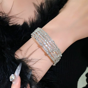 Detailopname van een luxe zilveren meerlaagse strass armband om de pols