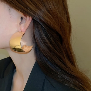 Close-up of model wearing large high-polished gold-plated wide C-shape hoop earrings
