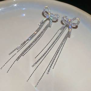 Macro shot of silver bow tassel earrings with sparkling rhinestones on ceramic