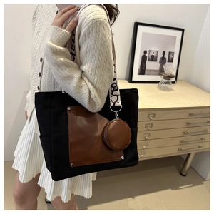 Close-up of contrast canvas tote bag with brown leather pocket and jacquard strap details