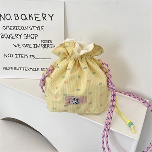 Close-up of yellow gingham drawstring bucket bag with cute patch and beaded rope detail