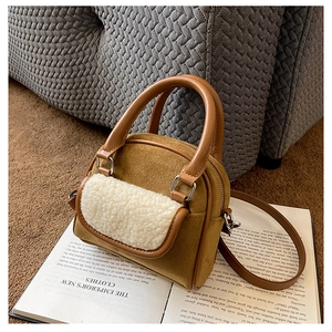 Detail of vintage brown suede handbag featuring white faux shearling front pocket and metal buckles