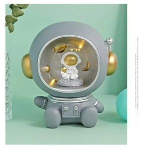 Illuminated astronaut crystal ball music box with golden resin base on mint background